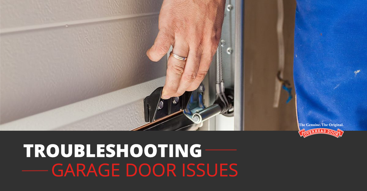 Two men repairing a brown garage door